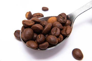 natural coffee beans in a metal teaspoon