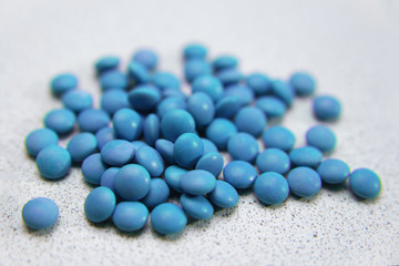 Fototapeta na wymiar scattering of blue pills dragee on a gray background