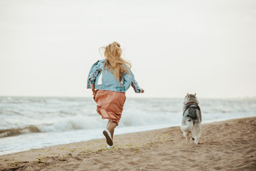 dog with girl running on the sea shore husky