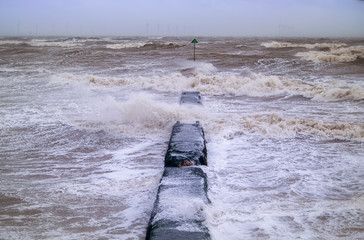 Angry sea during a storm hitting the groyne