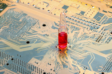 glass ampoule with a red vaccine stand on circuit board of microcircuit with contact tracks concept...