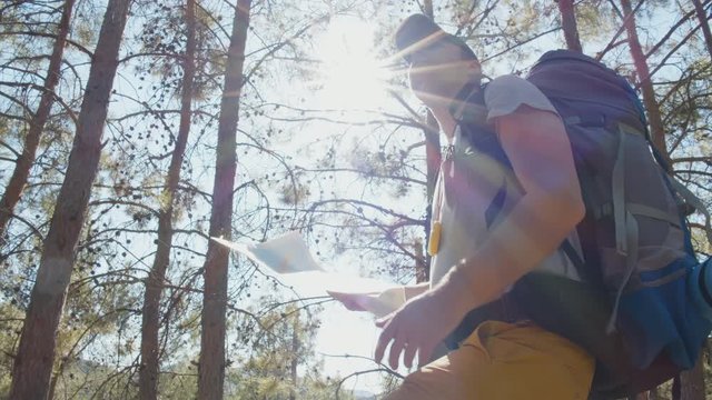 Hiker lost in forest tries to read map for directions