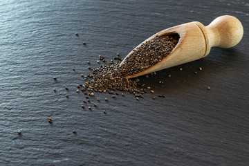 Seeds chia superfood background. Healthy pile flax seed in wooden spoon isolated on black. Salvia hispanica antioxidant grains on stone dark texture.