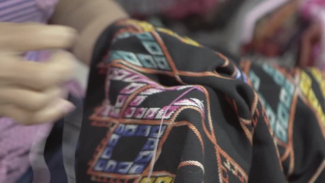 Close-up midsection of woman stitching black fabric for sale at street night market - Luang Prabang, Laos