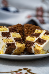 A close photo of a chessboard cake, the dough lies on a white plate.