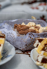 A piece of cake wrapped in a napkin with decorations, next to other cakes and plates.
