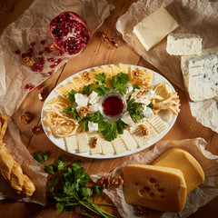 Cheese plate with different types of cheese with honey and nuts. Sliced pieces of cheese on a wooden table