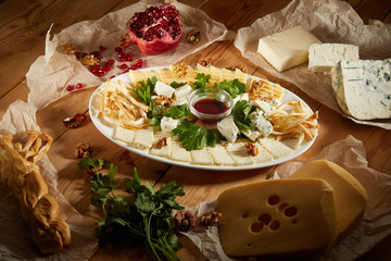 Cheese plate with different types of cheese with honey and nuts. Sliced pieces of cheese on a wooden table
