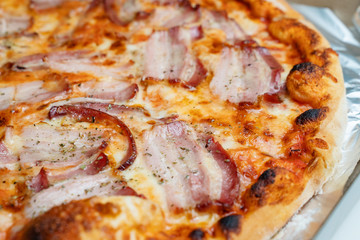 Close up on fresh tasty whole baked pizza with bacon and cheese on the table