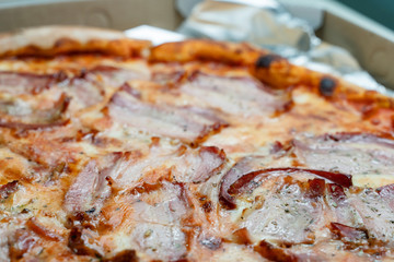 Close up on fresh tasty whole baked pizza with bacon and cheese on the table