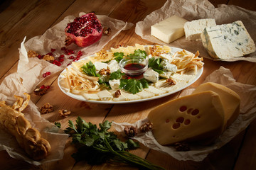Cheese plate with different types of cheese with honey and nuts. Sliced pieces of cheese on a wooden table