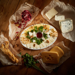 Cheese plate with different types of cheese with honey and nuts. Sliced pieces of cheese on a wooden table