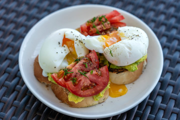 Two tasty sandwiches with boiled egg, green avocado and red tomato on plate, close up
