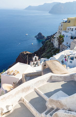 Bird view from the cliffs on village greek buildings and bell tower and ocean in Oia, Santorini, Greece