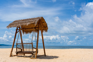 Wooden swing under a thatched roof on a sandy tropical beach near sea on island of Phu Quoc, Vietnam. Travel and nature concept