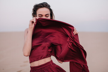 Girl with red cloth in the sunset rays in the desert