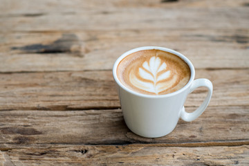 Cup of hot coffee with milk art on the surface placed on the wooden table
