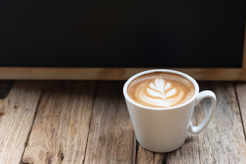 Cup of hot coffee with milk art on the surface placed on the wooden table