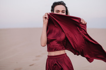 Naklejka premium Girl with red cloth in the sunset rays in the desert