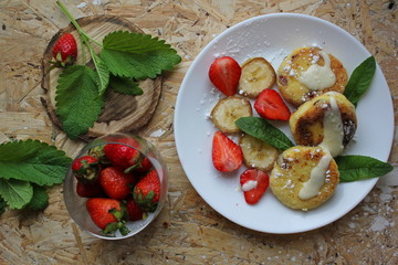 strawberry and cream. Cottage cheese pancakes cottage cheese with strawberry, mint, and banana. Ukrainian traditional food. Ukrainian national kitchen.