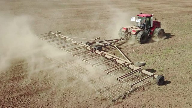 Aerial view of a powerful energy-saturated tractor with a large hook force, performing tillage for sowing winter crops with a disc cultivator in the autumn