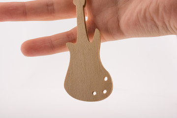 Close-up Of Human Hand Holding Small Wooden Guitar Against White Background