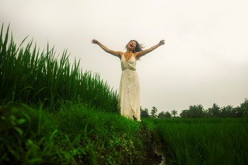mind and body connection with nature - middle aged attractive and happy Asian Chinese woman in Summer dress enjoying idyllic tropical destination dancing free