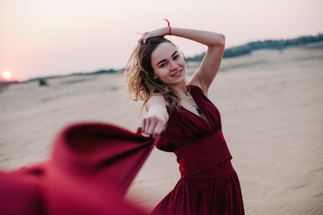 Portrait of a girl in a red dress at sunset in the desert