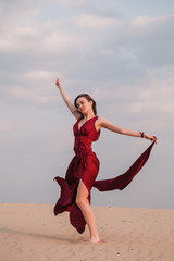 Obraz premium Girl in red dress at sunset in the desert