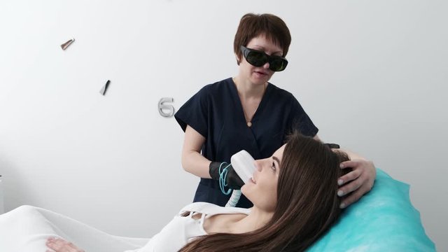 Pretty girl on laser hair removal procedure in beauty studio