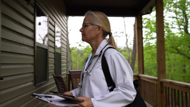 Closeup shot of side view of nurse or doctor arriving for home visit in rural area, with showing ID and smiling at door.