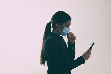 COVID-19 mask wearing woman touching her face while walking and texting mobile phone, Coronavirus prevention not properly using the protection.