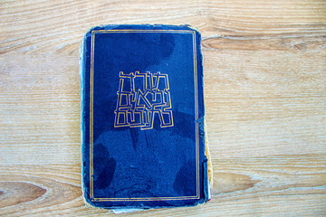 Old dusty Hebrew Bible book Tanakh (Tanach) on a background of wood (translated from Hebrew on the book Hebrew Bible Tanakh: Torah, Neviim, Ketuvim), Israel