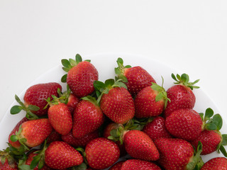 Top view. Copy space. Many strawberries in the white dish and white background.