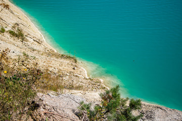 Unusual lake with turquoise water in the crater. Rocky stony shore chalk quarry in Belarus.