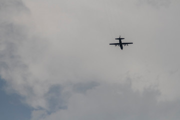 Naklejka na ściany i meble Silhouette of a lone plane in a gray sky with clouds