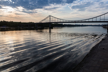 Fototapeta na wymiar Waves and sky reflection under the bridge on Dnipro river, Kyiv city, Ukraine