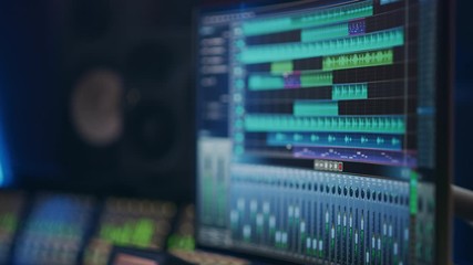 Music Recording Studio: Computer Screen Showing User Interface of DAW Digital Audio Workstation Software with Track Song Playing. In the Background Blurred Control Desk with Mixer and Equalizer