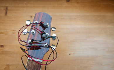 The neck of a classic six-string guitar with headphones on a yellow board. guitar and accessories. art and playing the guitar