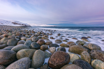 Waves break on the Gulf coast against the backdrop of snow-capped mountains of the Arctic 