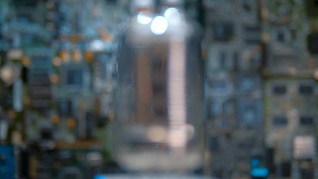 Old vacuum electronic lamp stands on the background of a modern digital electronic board. Macro. Closeup. Dolly shot. Shallow depth of field. Rotation. Focus pull