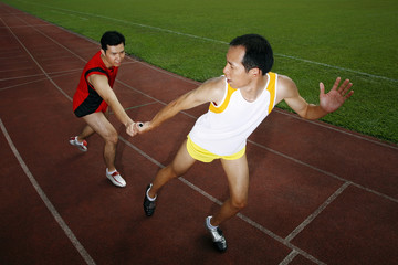 Man passing baton to his teammate in a relay event