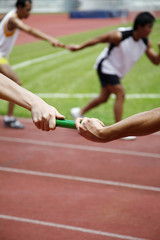 Man passing baton to his teammate in a relay event