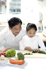 Senior man and girl preparing food in the kitchen