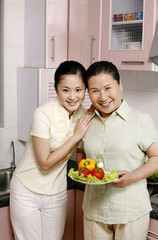 Two women posing with a bowl of vegetables