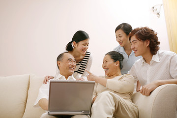 Fototapeta premium Senior man and woman using laptop with family members watching