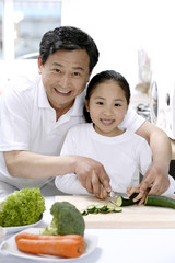 Naklejka premium Senior man and girl preparing food in the kitchen