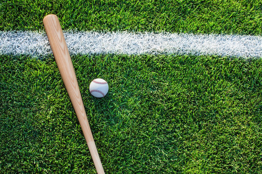 High Angle View Of Baseball Bat With Ball On Grassy Field