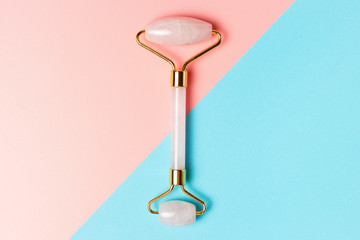 Jade roller on blue and pink background, top view