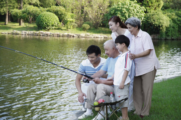 Family watching senior man fishing at the lake